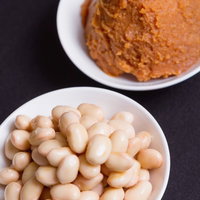 白い皿に盛った味噌と大豆の写真