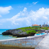 堤防やボートが見える池間島の海岸沿いの街並みと青い海の写真