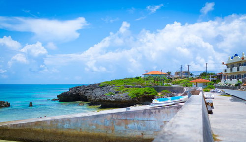 堤防やボートが見える池間島の海岸沿いの街並みと青い海