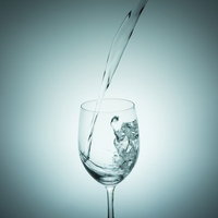 ワイングラスに勢いよく水を注ぐ瞬間の写真