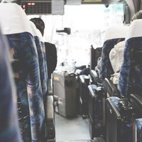 青い柄付きシートが並ぶ通路にキャリーケースが置かれたバスの車内の写真