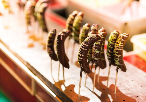 串に刺さってチョコと抹茶がかかった屋台のチョコバナナ