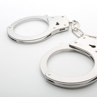 白背景に置かれた銀色の手錠と鍵の写真