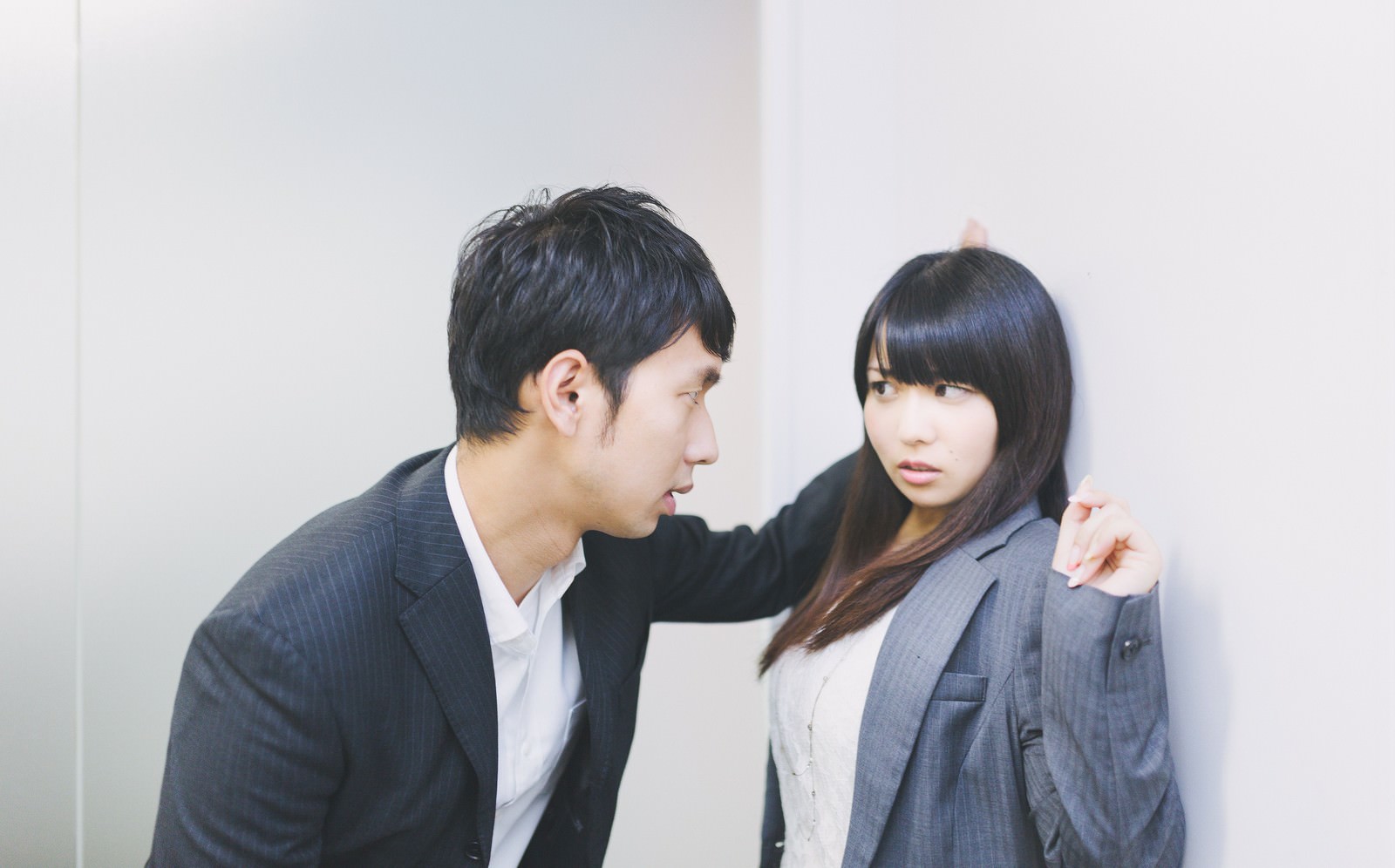 職場で壁際に追い詰められる女性［モデル：Lala 大川竜弥］