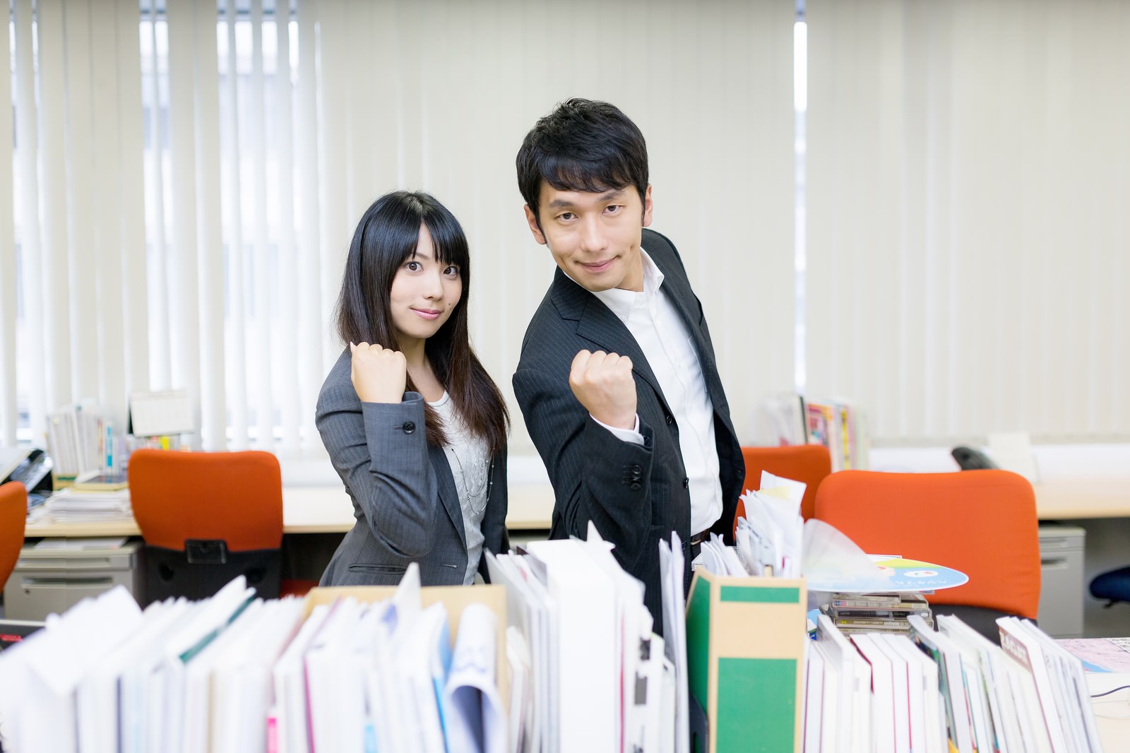 オフィスで拳を握ってやる気ポーズのスーツの男女［モデル：大川竜弥 Lala］