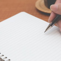 ノートにペンで記入するメモの様子、手書き執筆の手元作業の写真