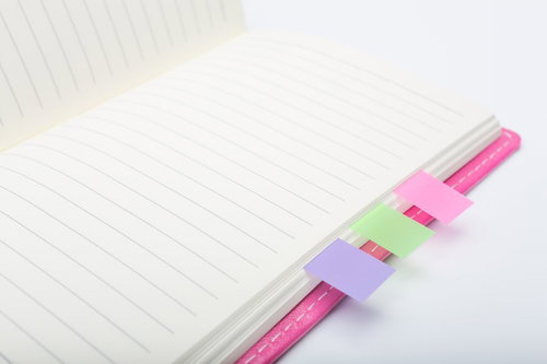 カラフルな付箋が挟まったピンクの手帳