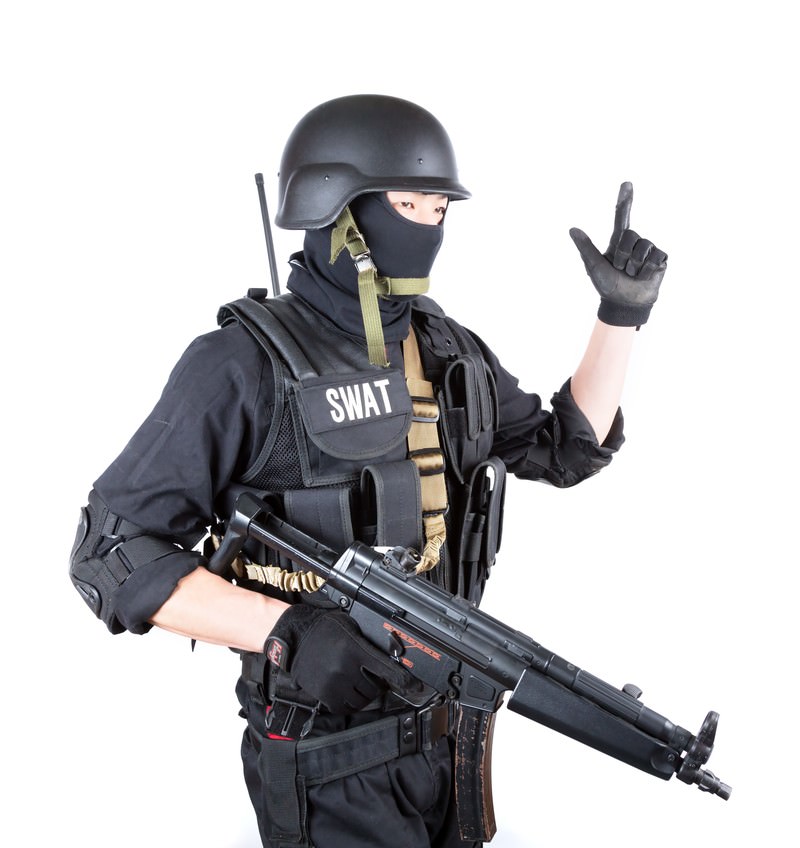 白背景でピストルのハンドサインを出すSWAT隊員［モデル：モデルリリース］