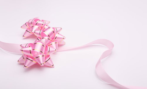 白い面に置かれたピンクのラッピングリボン