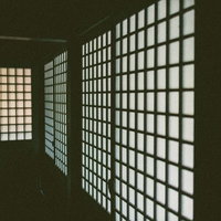 半透明の白い紙が貼られた和室の格子状の障子が並ぶ廊下の写真