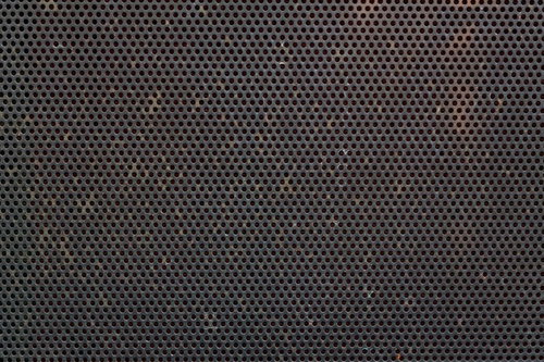 規則正しい丸い穴が並ぶ錆びたメッシュ金属のテクスチャー