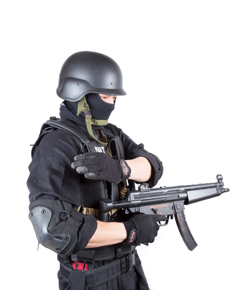 SWAT装備の人物がサブマシンガンを持ちハンドサインを出すポーズ［モデル：モデルリリース］
