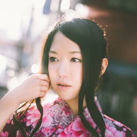 花柄浴衣で髪に手を添えるぼけた街並み背景の女性の写真