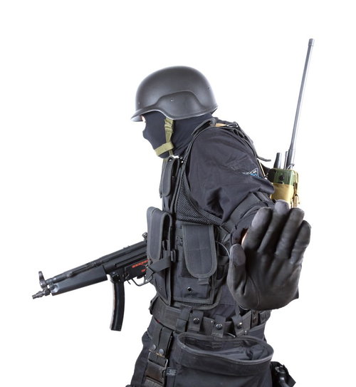 白背景で停止のハンドサインを出す装備の隊員