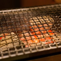 炭火の熱で赤く光る網焼きの炭火焼き網とバーベキューコンロの写真