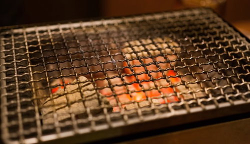 炭火の熱で赤く光る網焼きの炭火焼き網とバーベキューコンロ