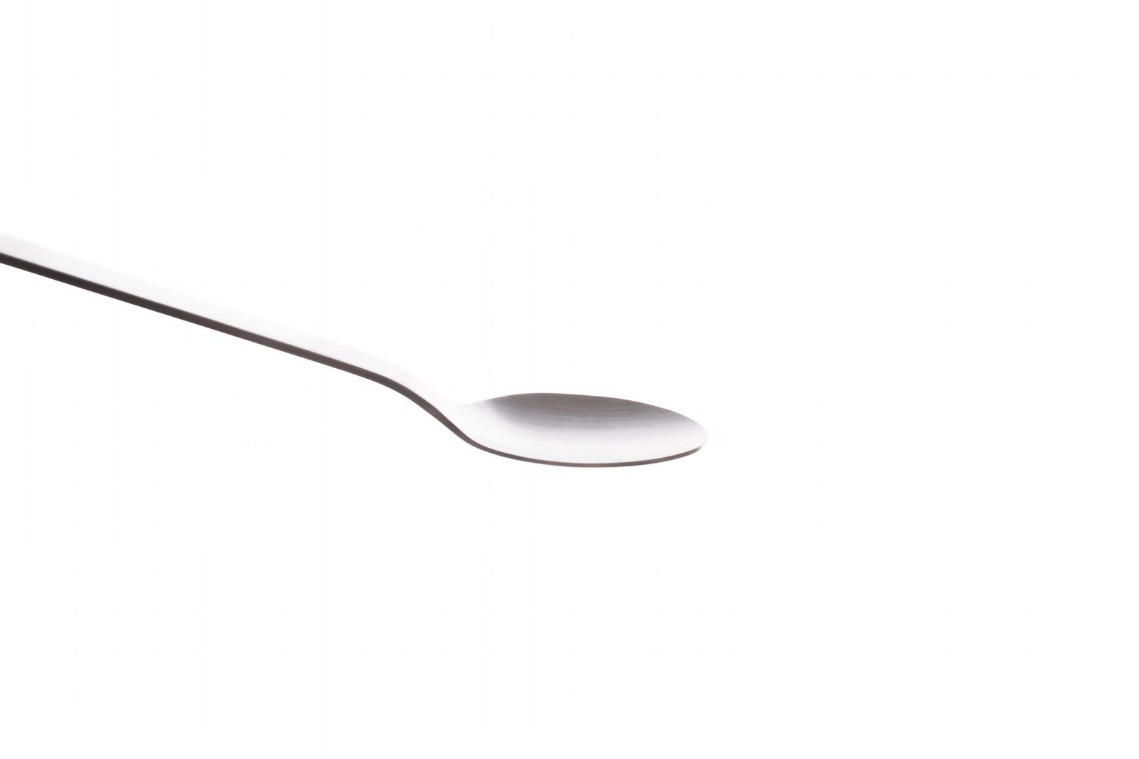 白い背景の上に置かれたカーブした銀色のスプーン