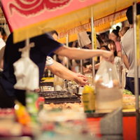 夜の屋外でピンクと黄色の屋根が並ぶたこ焼きの屋台の写真