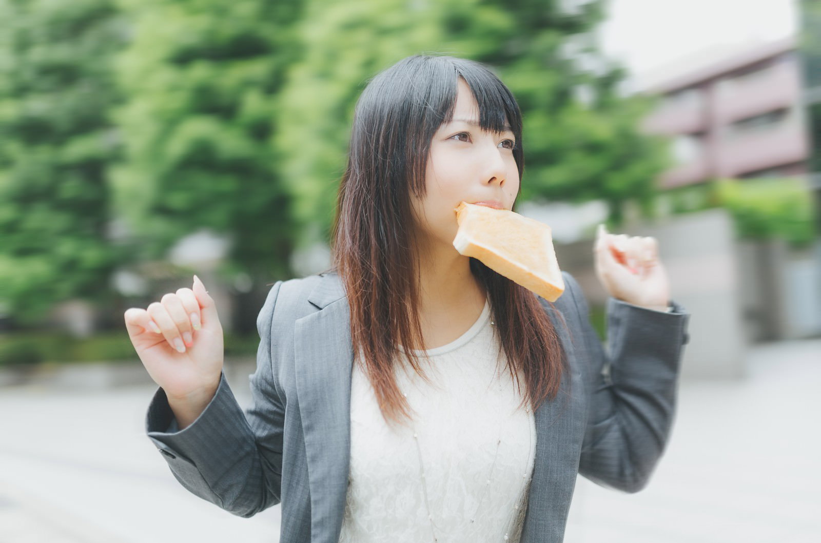トーストを咥えて走るスーツ姿の女性社員［モデル：Lala］