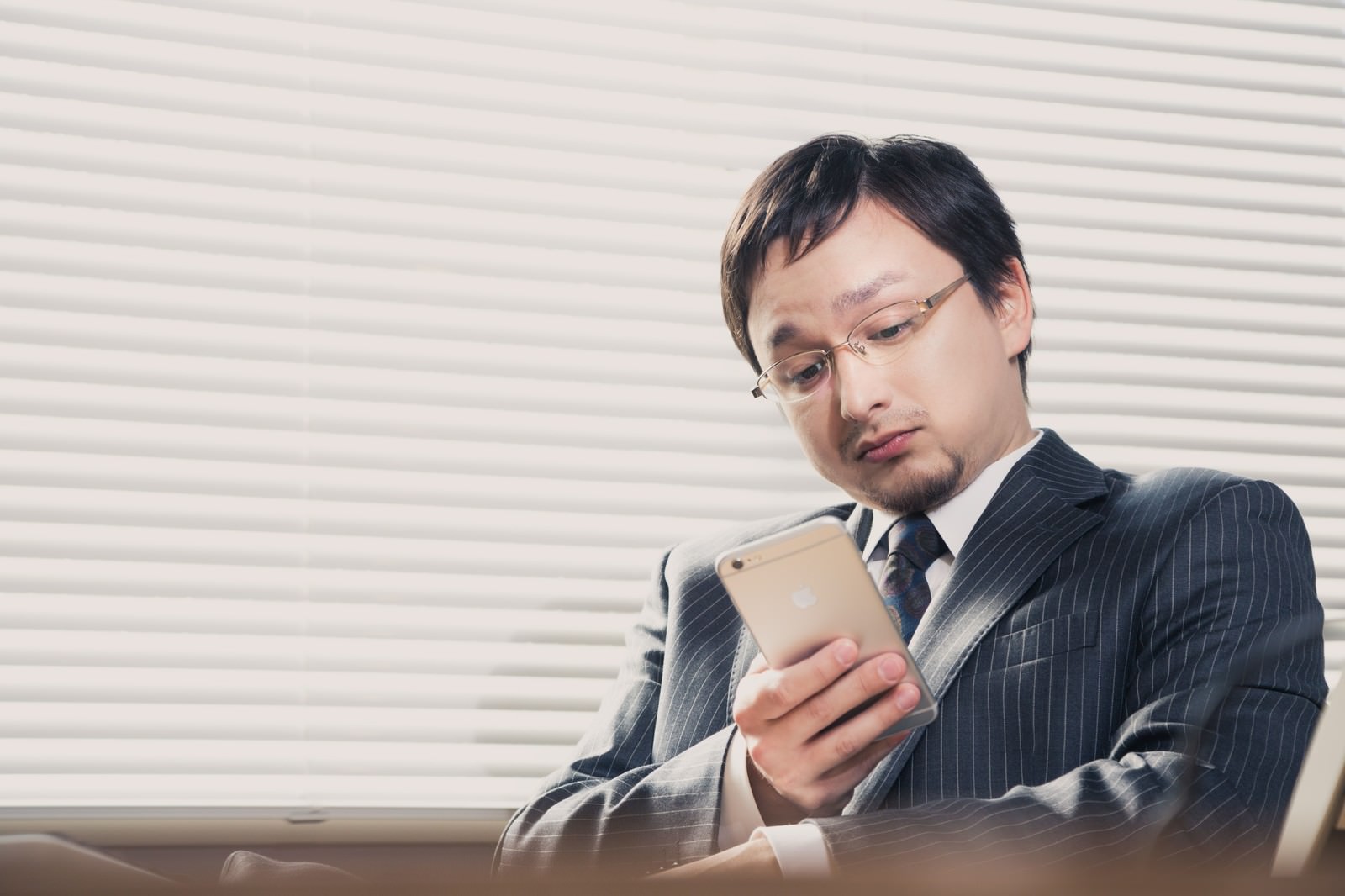 スマートフォンを操作するスーツ姿の男性［モデル：Max_Ezaki］