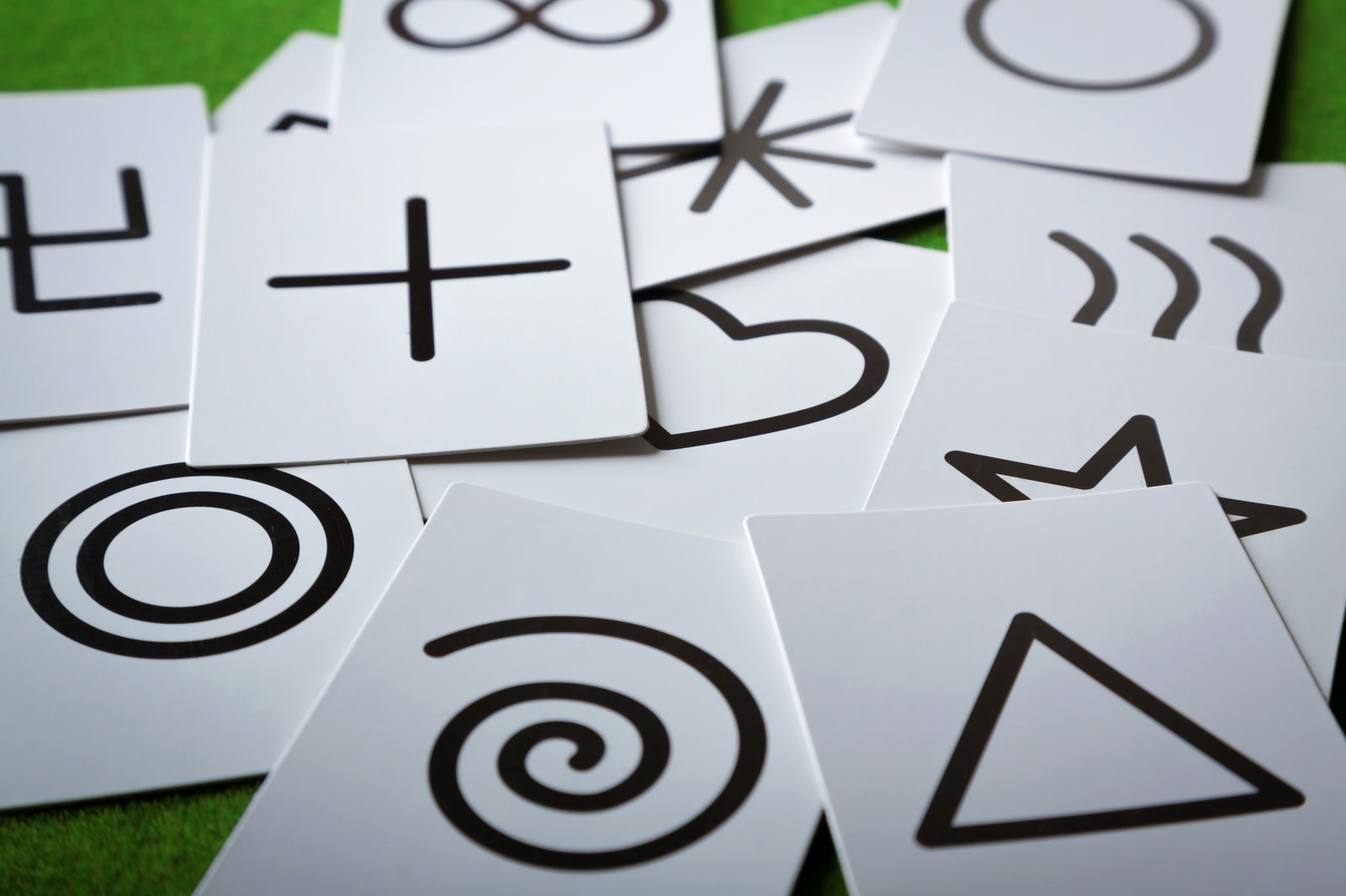白いカードに黒い数字と記号が描かれ、緑背景の上に積み重ねられている占いカード