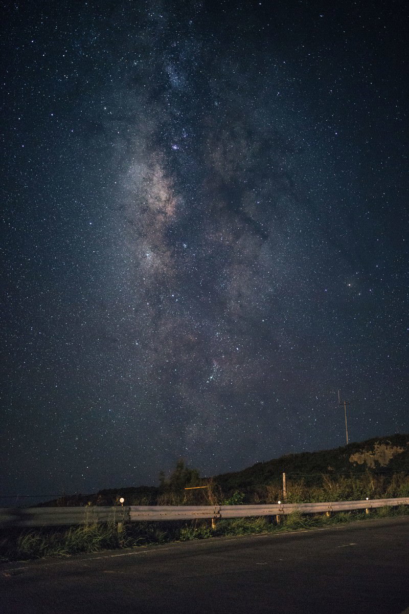 夜空に広がる天の川と道路のガードレール