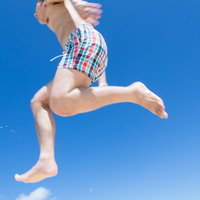 宮古島の海で海パン姿で飛び跳ねてはしゃぐ男子の写真