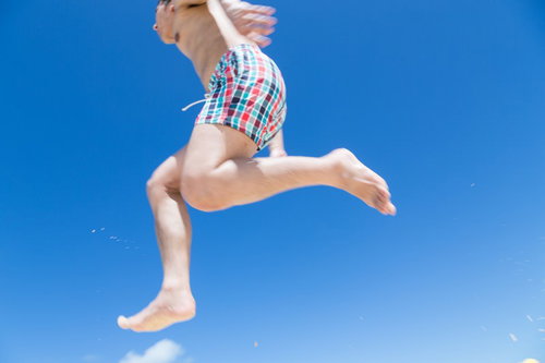 宮古島の海で海パン姿で飛び跳ねてはしゃぐ男子