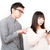 スマホに夢中の彼女と相手にしてもらえない彼氏の写真