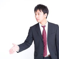 右手を差し出して握手を求めるスーツのビジネスマンの写真