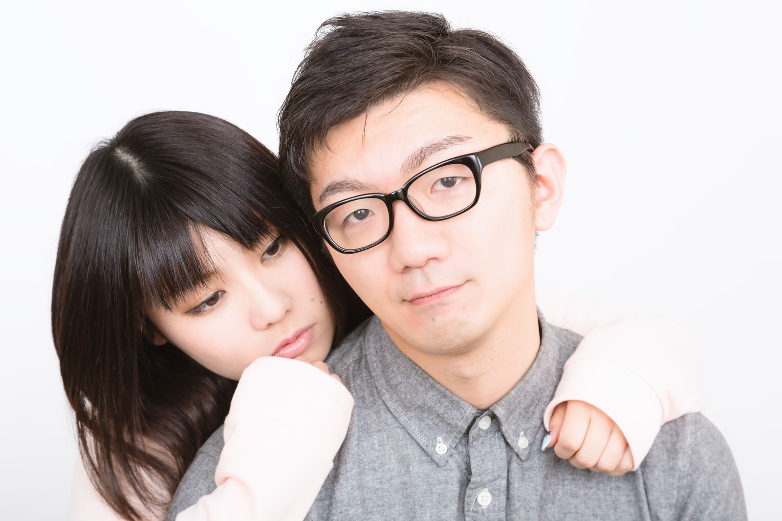 白背景で後ろからべったりする彼女とドヤ顔の眼鏡の彼氏［モデル：OZPA Lala］