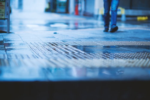 雨に濡れた駅のホームと点字ブロック