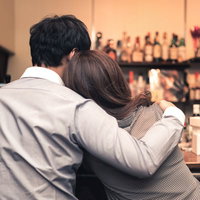 バーで密着するお忍びカップルの写真