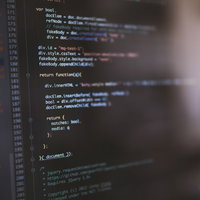 コードが書かれたモニターを見るエンジニアの写真