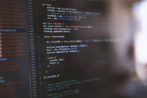 コードが書かれたモニターを見るエンジニア