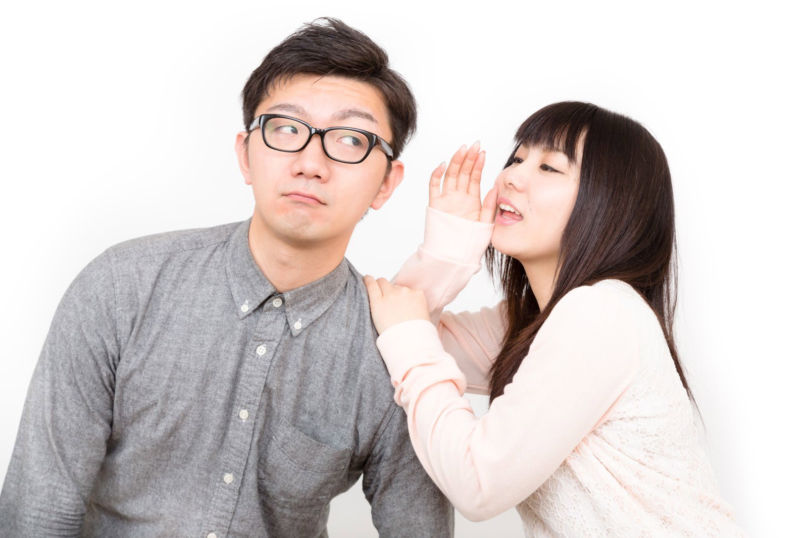 手を口元に当てて彼氏に内緒話をする黒髪の彼女［モデル：OZPA Lala］