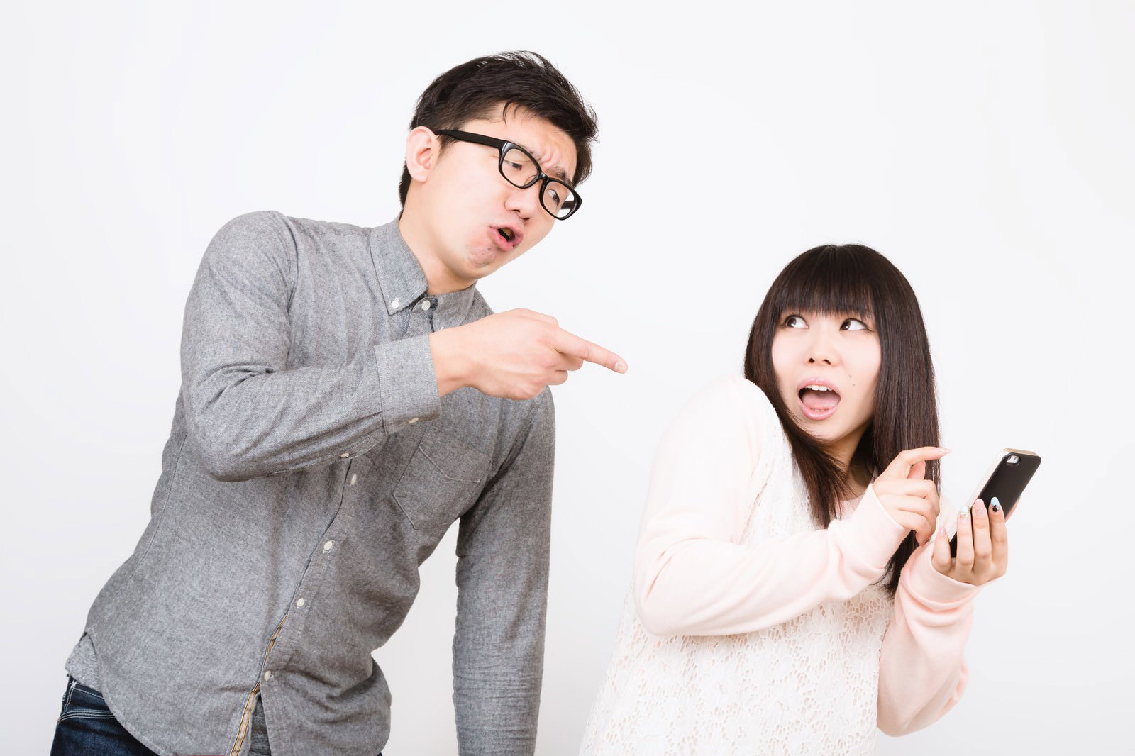 女性のスマホ画面を指差して怒る彼氏の男性［モデル：OZPA Lala］