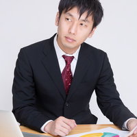 円グラフの資料を持つスーツ姿の男性の写真