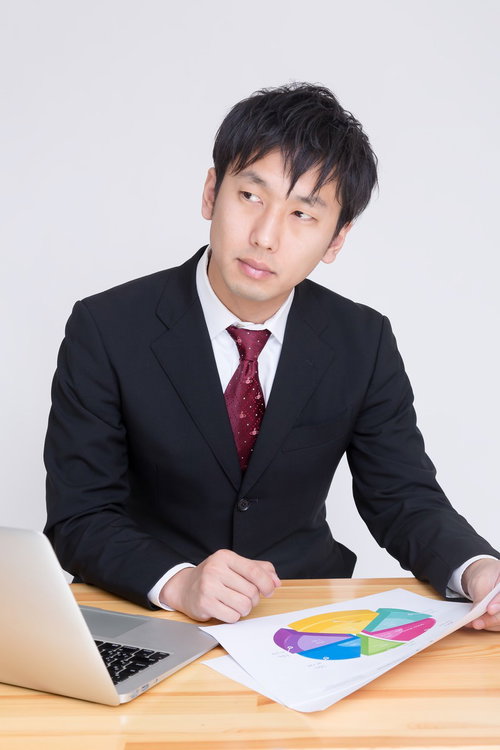 円グラフの資料を持つスーツ姿の男性