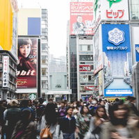 大型ビルや広告看板が並ぶ道頓堀戎橋の大勢の歩行者が行き交う交差点の写真