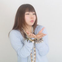 両手を前に出すアクセサリーをつけた水色の服の女性の写真