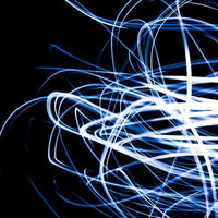 真っ黒な背景に青と白の光の曲線が交差して流れる光の軌跡の写真