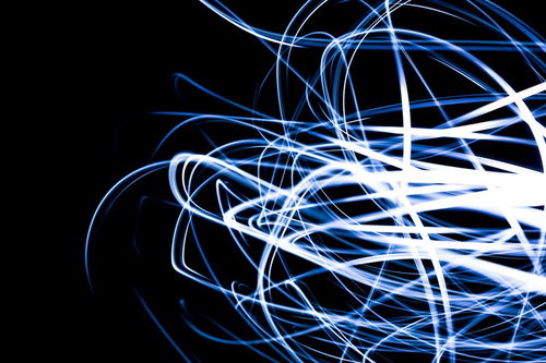 真っ黒な背景に青と白の光の曲線が交差して流れる光の軌跡