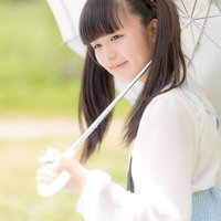 白い傘をさして屋外に立つツインテールの女の子の写真