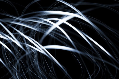 真っ黒な背景に白い光跡が重なり模様を描く長時間露光写真