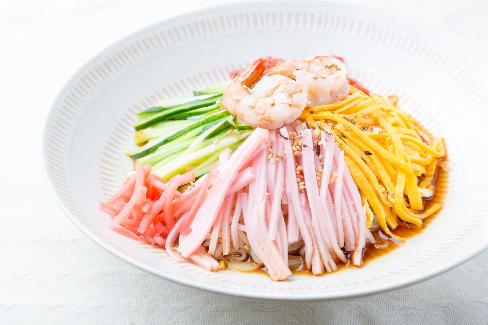 白い皿に盛り付けた冷やし中華、エビとハムときゅうり乗せ