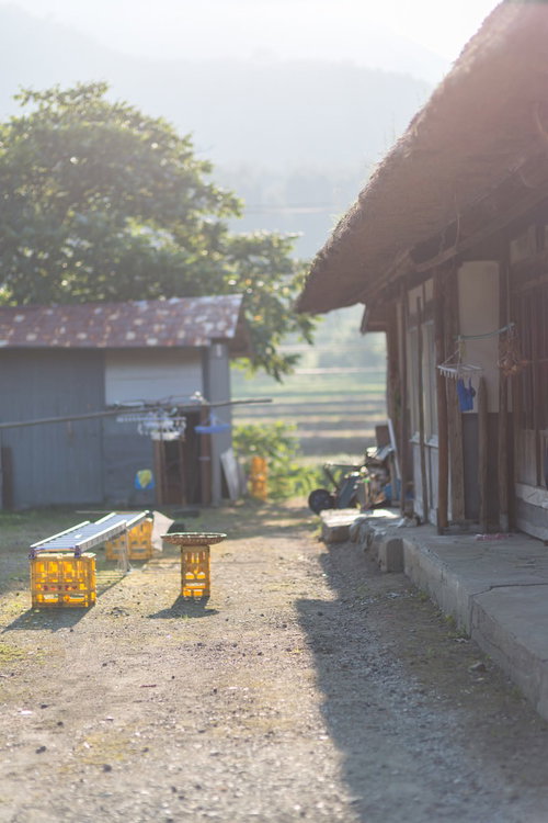 古民家の庭先に置かれた黄色い箱と籠