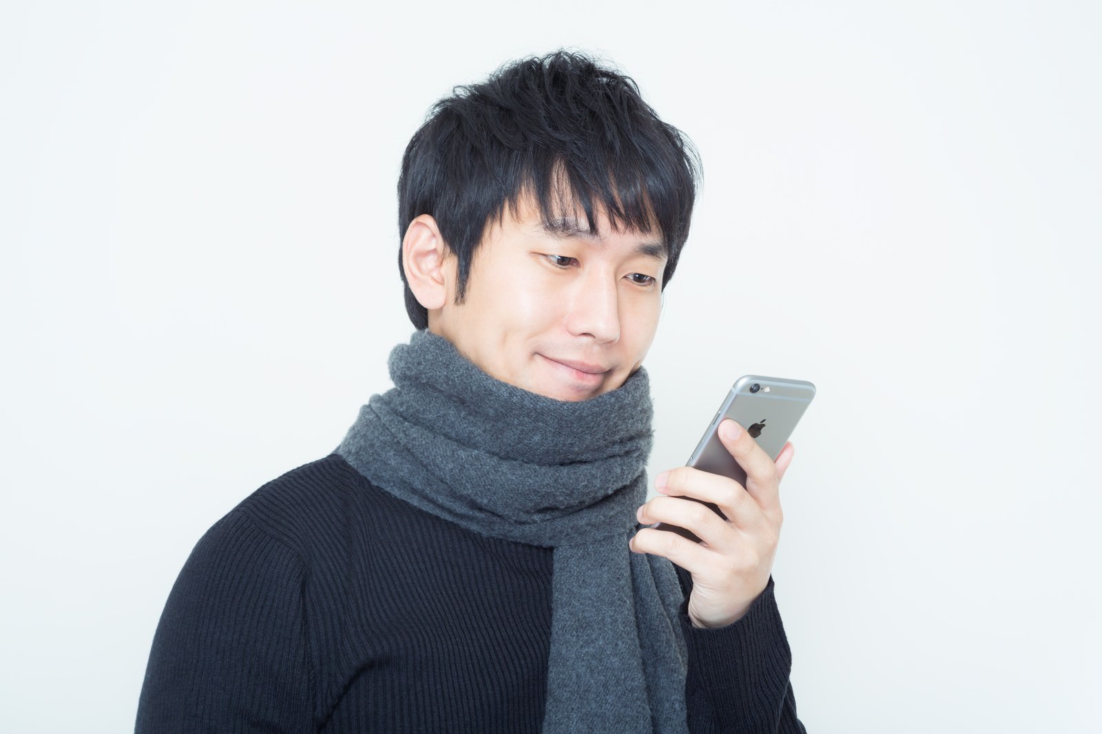 マフラーを巻いてスマホを両手で見る男性［モデル：大川竜弥］