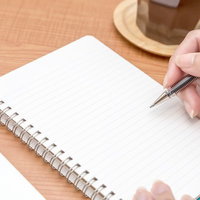 コーヒーとスマートフォンを横にノートに書き込む俯瞰の写真