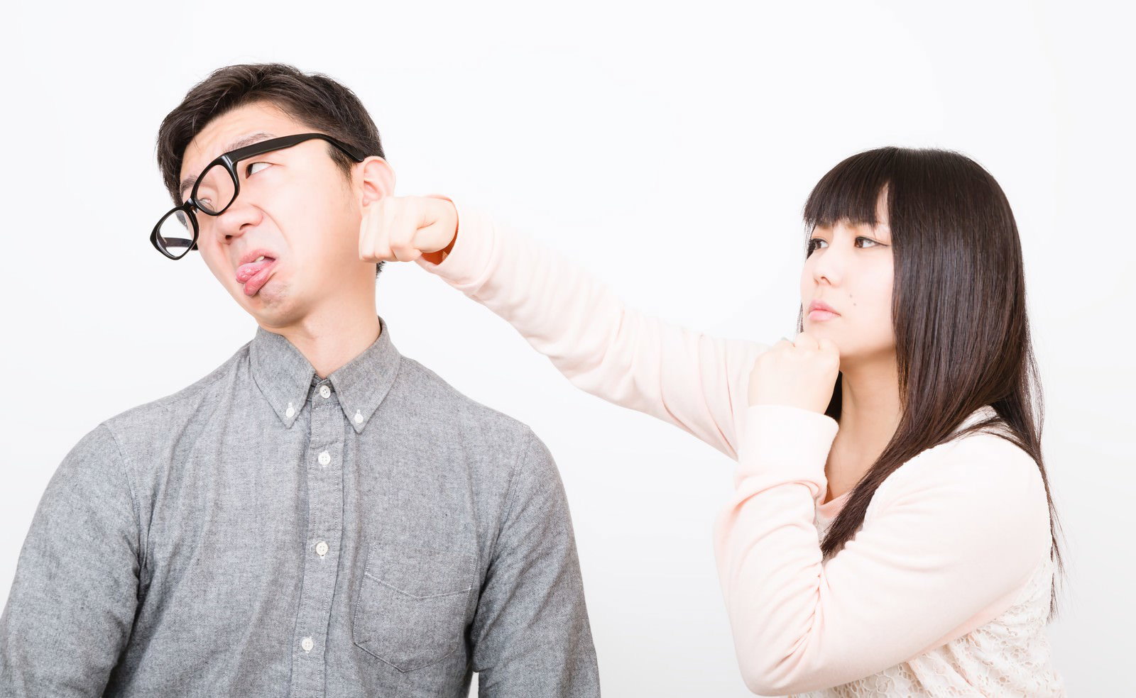 頬をつねられて顔をしかめる彼氏と笑顔の彼女［モデル：OZPA Lala］